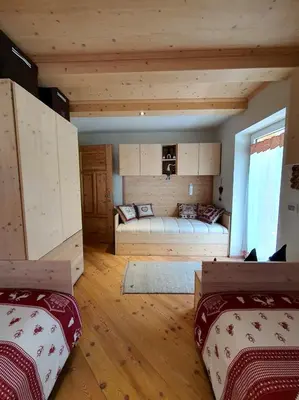 a bedroom with two beds in a room with wooden ceilings at Casa Sandra Moena by Go new Location in Moena