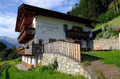 a house on a hill with a stone wall at Ausserstauderhof in San Leonardo in Passiria