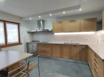a kitchen with wooden cabinets and a sink and a table at Casa Elisa apartment in Ronzone