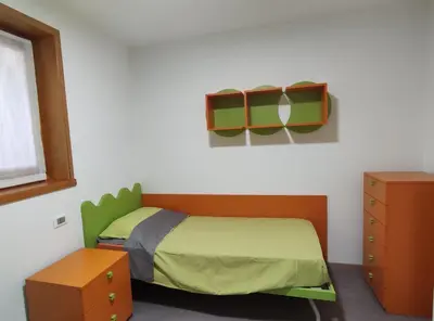 a small bedroom with a bed and a dresser at Casa Elisa apartment in Ronzone