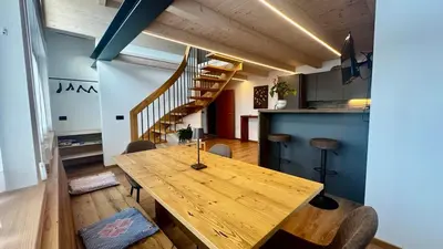 a dining room with a wooden table and stairs at Lares - Your nordic stay in Tesero