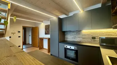 a kitchen with gray cabinets and a stove top oven at Lares - Your nordic stay in Tesero