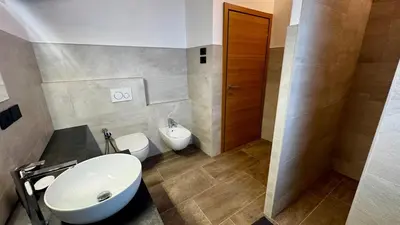 a bathroom with a white sink and a toilet at Lares - Your nordic stay in Tesero