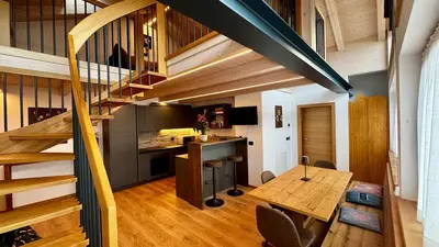 a room with a staircase and a table and a kitchen at Lares - Your nordic stay in Tesero