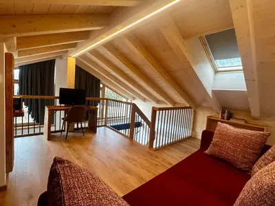 a living room with a couch and a desk with a television at Lares - Your nordic stay in Tesero