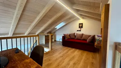 a living room with a red couch in the attic at Lares - Your nordic stay in Tesero