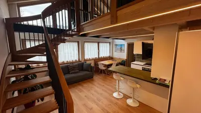 a living room with a staircase leading to a loft at Pecio - Your nordic stay in Tesero