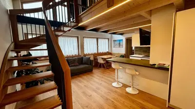 a room with a staircase and a living room with a table at Pecio - Your nordic stay in Tesero