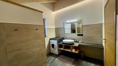 a bathroom with a sink and a washing machine at Pecio - Your nordic stay in Tesero