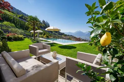 a garden with a couch and chairs and a pool at Gattererhof in Schenna