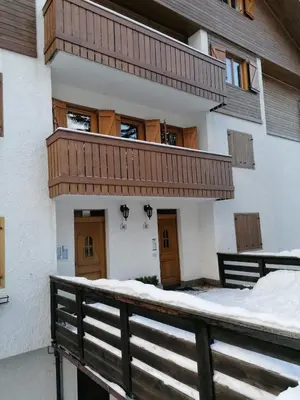 a building with a balcony with snow on the ground at Appartamento ai piedi delle Dolomiti in Selva di Val Gardena