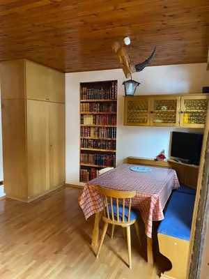 a dining room with a table and a book shelf at Appartamento ai piedi delle Dolomiti in Selva di Val Gardena