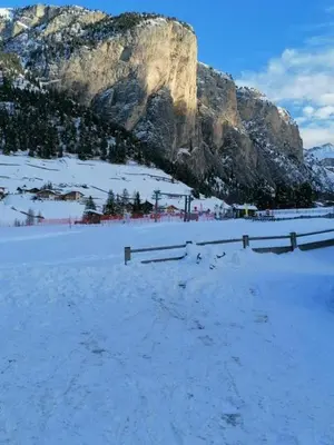 a snow covered field with a mountain in the background at Appartamento ai piedi delle Dolomiti in Selva di Val Gardena