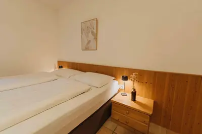 a bedroom with a white bed and a night stand with a lamp at Appartements Elke in Lagundo