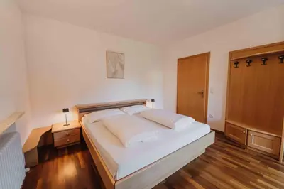 a bedroom with a large white bed and a wooden floor at Appartements Elke in Lagundo