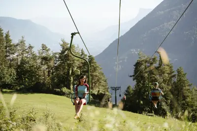 two people riding on a ski lift in the mountains at Appartements Elke in Lagundo
