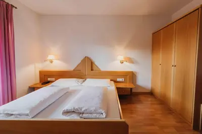 a bedroom with a large white bed and wooden cabinets at Appartements Elke in Lagundo