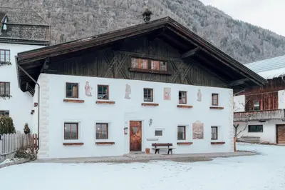 a white building with a wooden roof in the snow at B&B Öboluckna in Molini di Tures