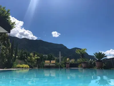 a large swimming pool with mountains in the background at Ferienwohnung in Schenna mit Bergblick und Pool - Unterpenatz in Schenna