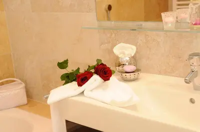 a bathroom sink with towels and roses on it at Ferienwohnung in Schenna mit Bergblick und Pool - Unterpenatz in Schenna