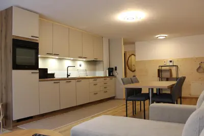 a kitchen with white cabinets and a table with chairs at Apartment Claudia in Bressanone