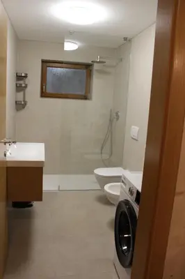 a bathroom with a toilet and a sink and a washing machine at Apartment Claudia in Bressanone