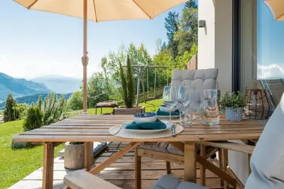 a wooden table with plates and wine glasses on it at Villa Waldrand with Merano view in Lana
