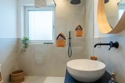 a bathroom with a white sink and a window at Villa Waldrand with Merano view in Lana