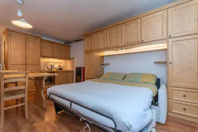a bedroom with a bed and a table and cabinets at Suite Monte Pelsa in Alleghe
