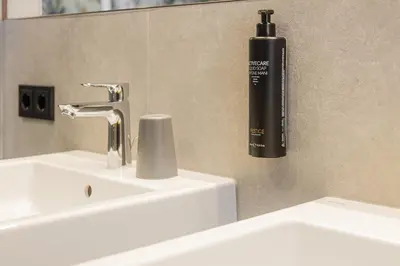 a bathroom sink with a black soap dispenser on the wall at CHALET ARIA Stay Mountain Relax in Arabba
