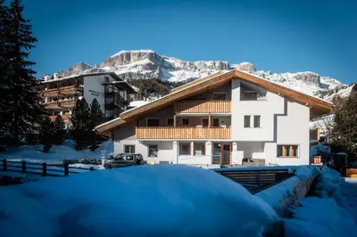 a house in the snow with mountains in the background at CHALET ARIA Stay Mountain Relax in Arabba