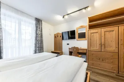 a bedroom with two beds and a desk at CHALET ARIA Stay Mountain Relax in Arabba