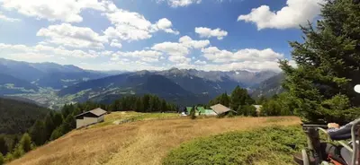 a grassy hill with houses and mountains in the background at Hühnerspielhütte - Rifugio Gallina - Mountain Hut Hühnerspielhütte in Moncucco