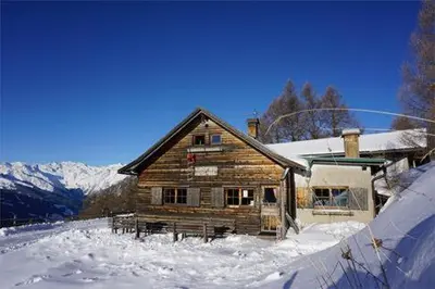 a log cabin in the snow with mountains in the background at Hühnerspielhütte - Rifugio Gallina - Mountain Hut Hühnerspielhütte in Moncucco