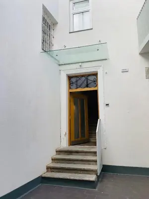 a white building with a wooden door and stairs at Amort Suites Meran in Merano