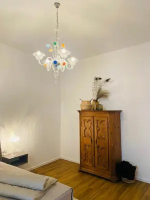 a bedroom with a chandelier and a wooden cabinet at Amort Suites Meran in Merano