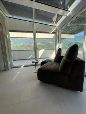 a living room with a couch in front of a large window at Vista Dolomiti in Bressanone