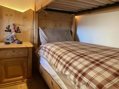 a bedroom with a bed with a plaid bedspread and a wooden cabinet at Ai Vòlti in Cavalese