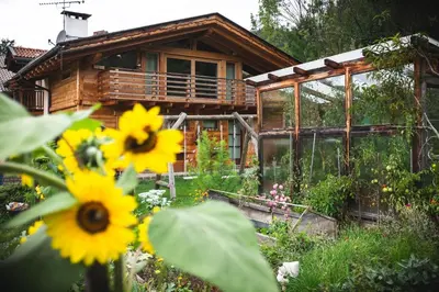 a wooden house with flowers in front of it at B&B Profumi nel bosco in Carano