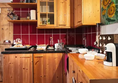 a kitchen with wooden cabinets and red tiles at B&B Profumi nel bosco in Carano