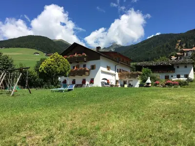 a house in a field with a green field at Pension Aichner in Terento