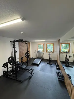 a gym with several treadmills and machines in a room at Pension Aichner in Terento