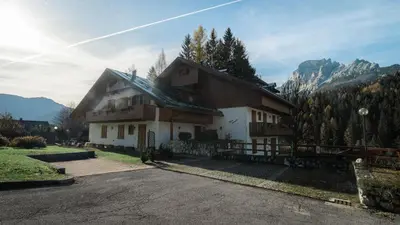 a house in the mountains with the sun shining at Elegante Attico a San Vito in San Vito di Cadore