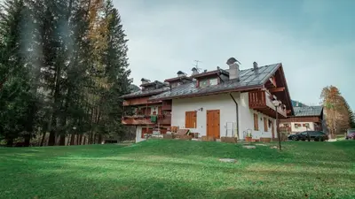 a house with a green lawn in front of it at Elegante Attico a San Vito in San Vito di Cadore