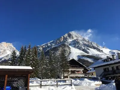 a snow covered mountain in front of a building at Elegante Attico a San Vito in San Vito di Cadore