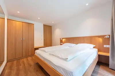 a bedroom with a large white bed with a wooden headboard at Apartments Greva 2 in Santa Cristina in Val Gardena