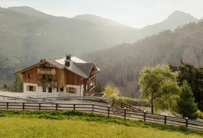 a house on a hill with mountains in the background at Ciasa Linde in Longega