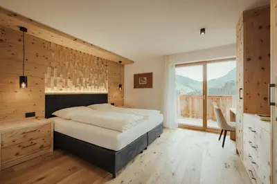 a bedroom with a large bed with a wooden headboard at Ciasa Linde in Longega