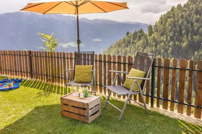 two chairs and an umbrella on top of a yard at Rabensteinhof - Urlaub auf dem Bauernhof in Parcines
