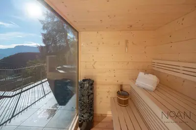 a wooden sauna with a bench on a balcony at NoAN Panorama Suiten - D i c k e n s in San Genesio Atesino